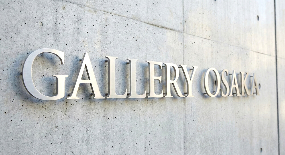 コンクリート打ちっぱなしの壁に設置されたステンレス切り文字