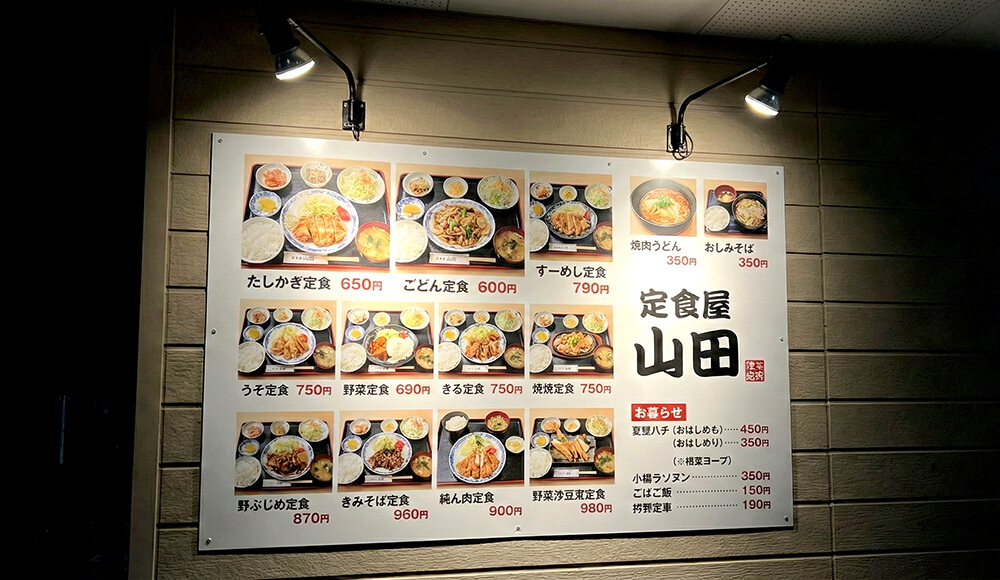 夜間、アームライトで照らされた壁面のプレート看板